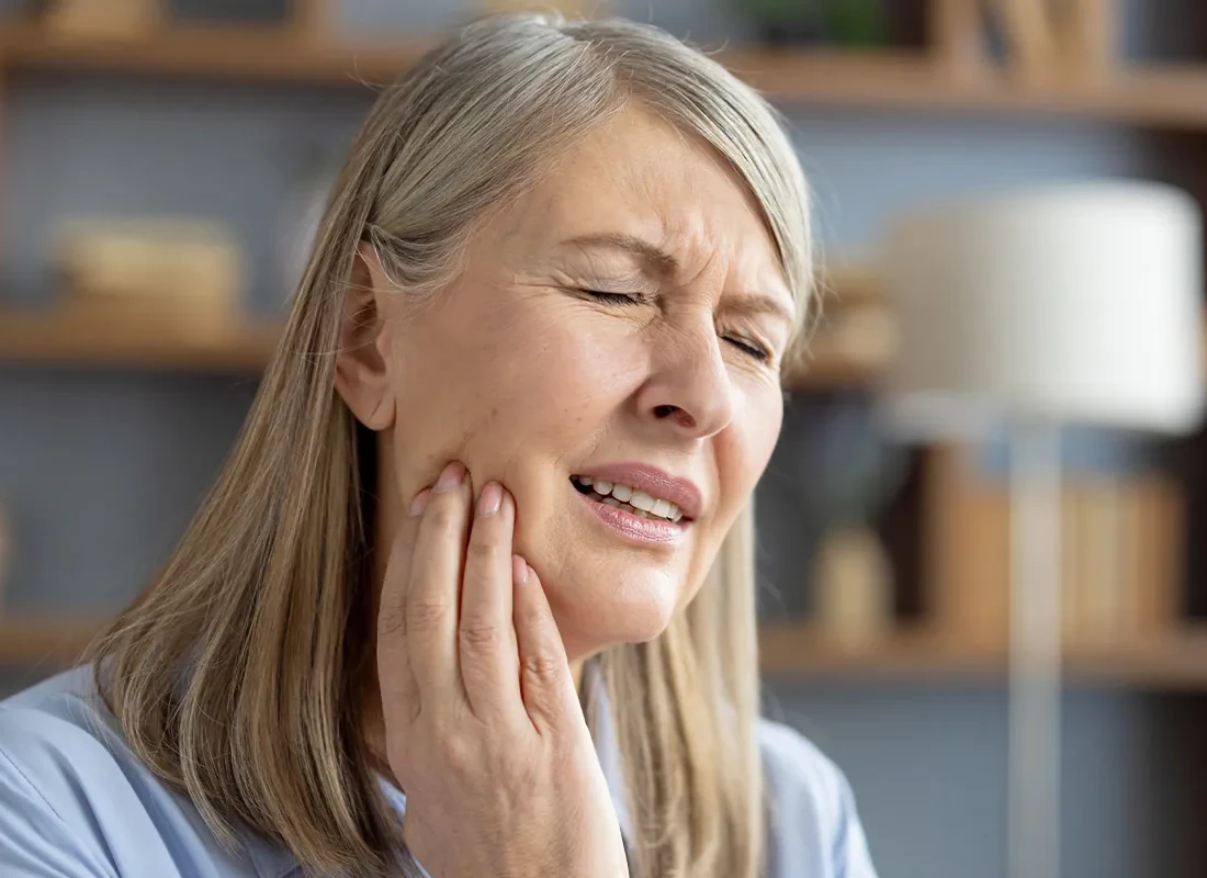 A patient holding their jaw in pain from a cracked molar